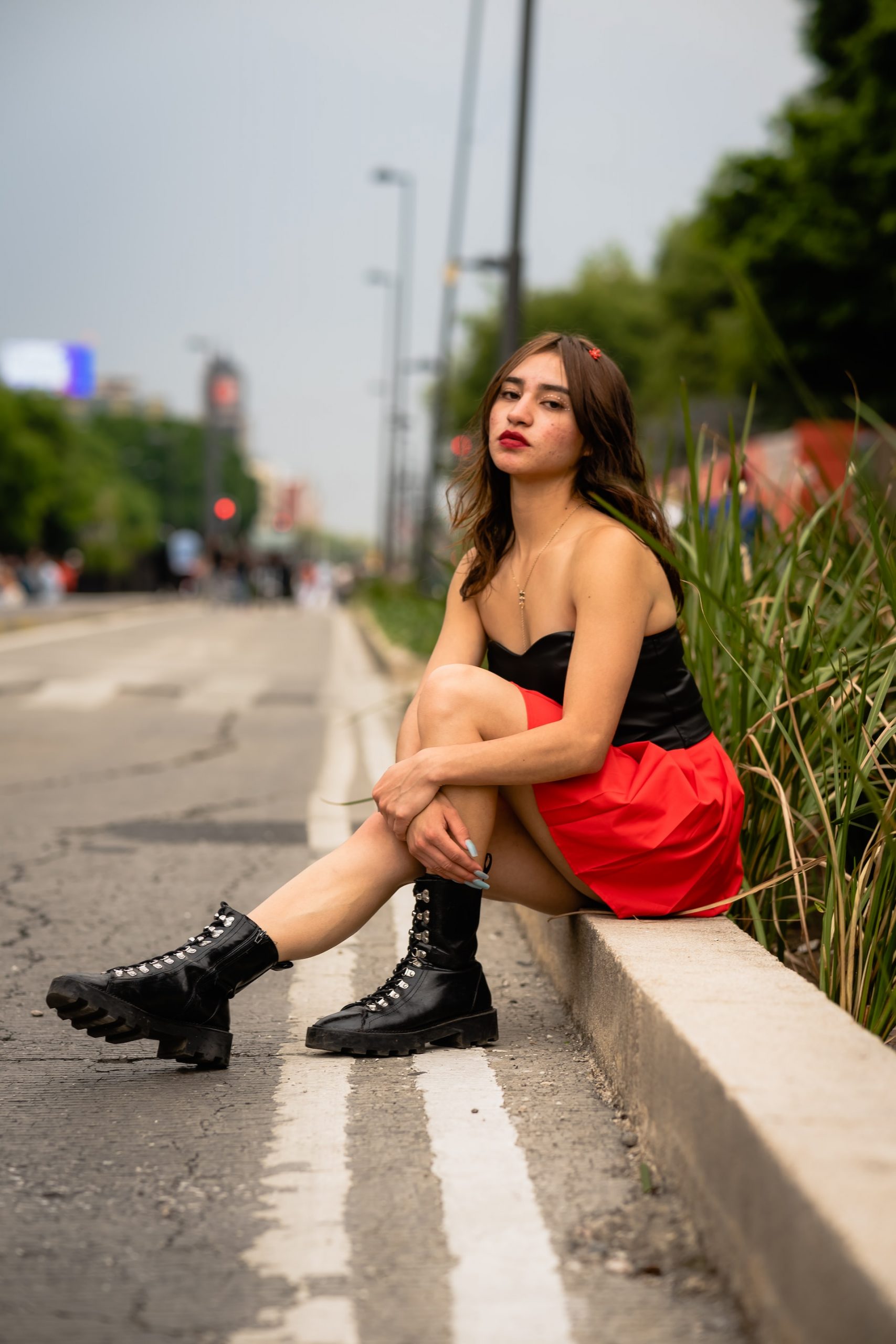 Mexican Model wearing the black top and red shorts sitting on the edge of road