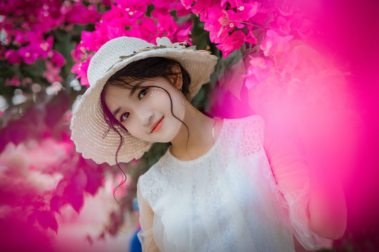 korean girl smiling and surrounded by pink flowers