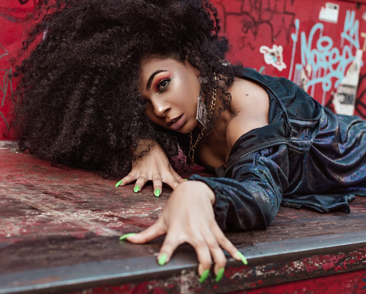 Black woman wearing a black top showing her green nails