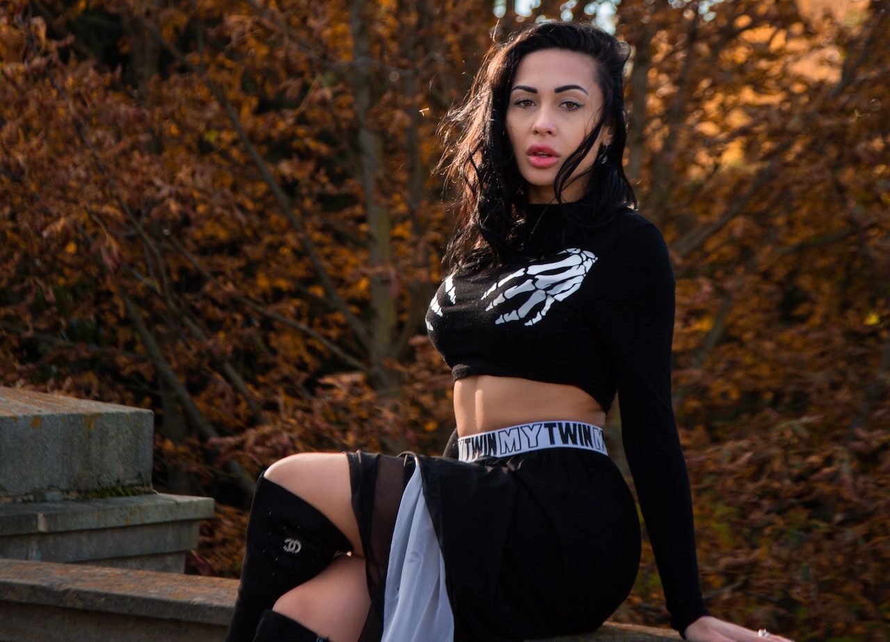 Eurpean girl wearing a black top and black pant sitting over a steps