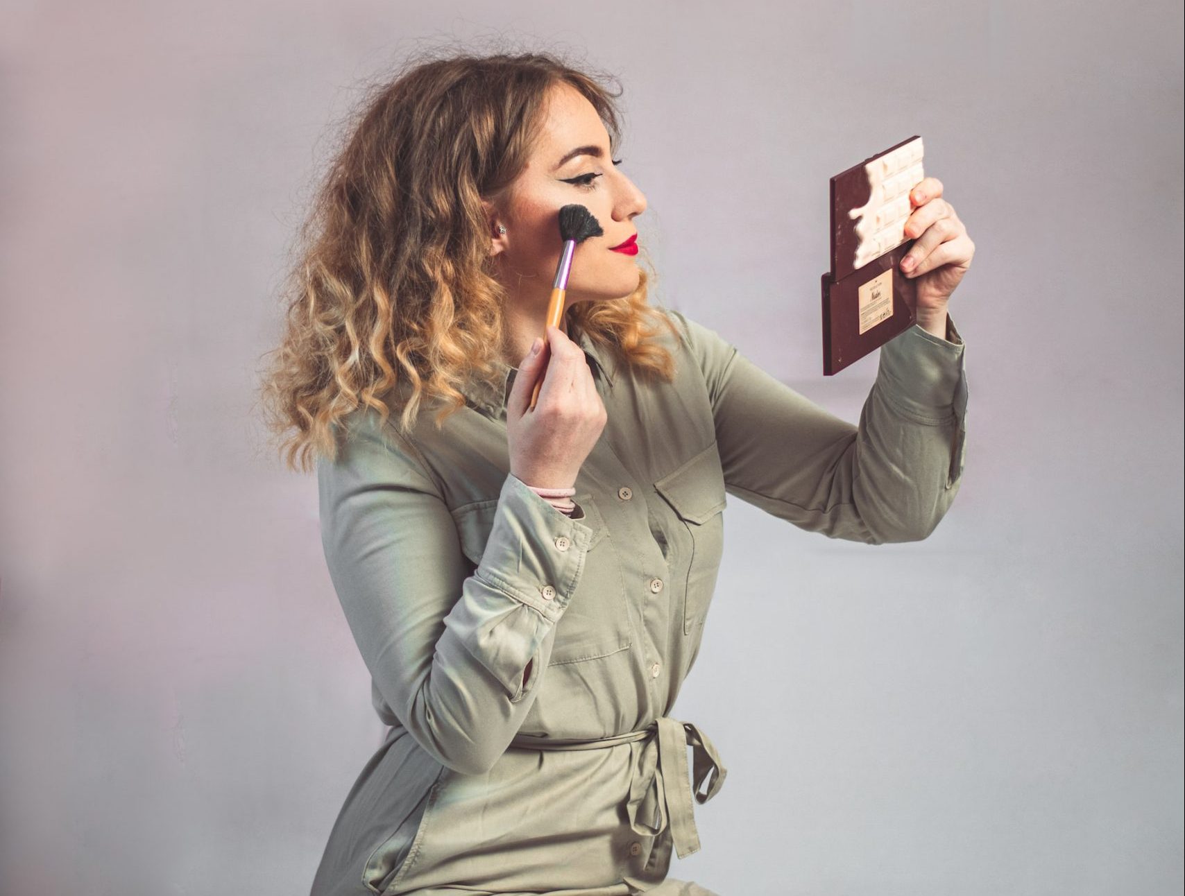 woman watching at mirror and doing makeup