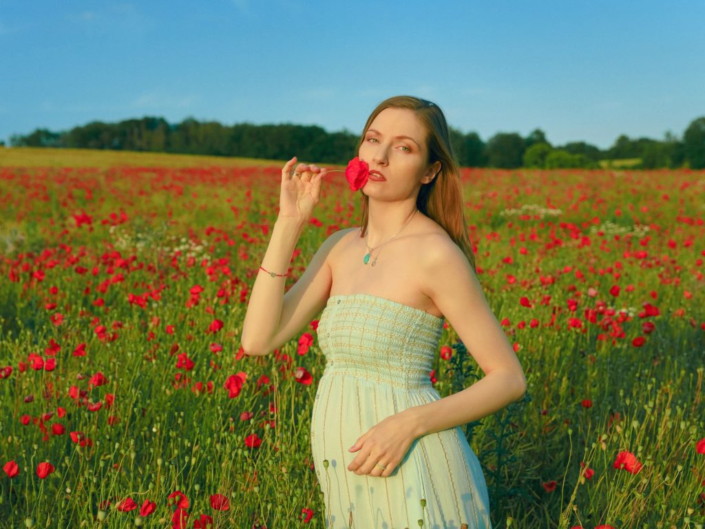 European beautiful girl holding red flower standing in the garden