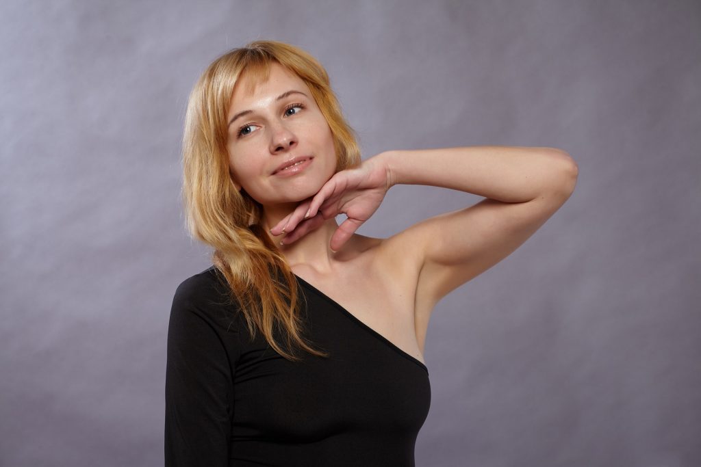 Woman wearing black top touching her left hand to her chin