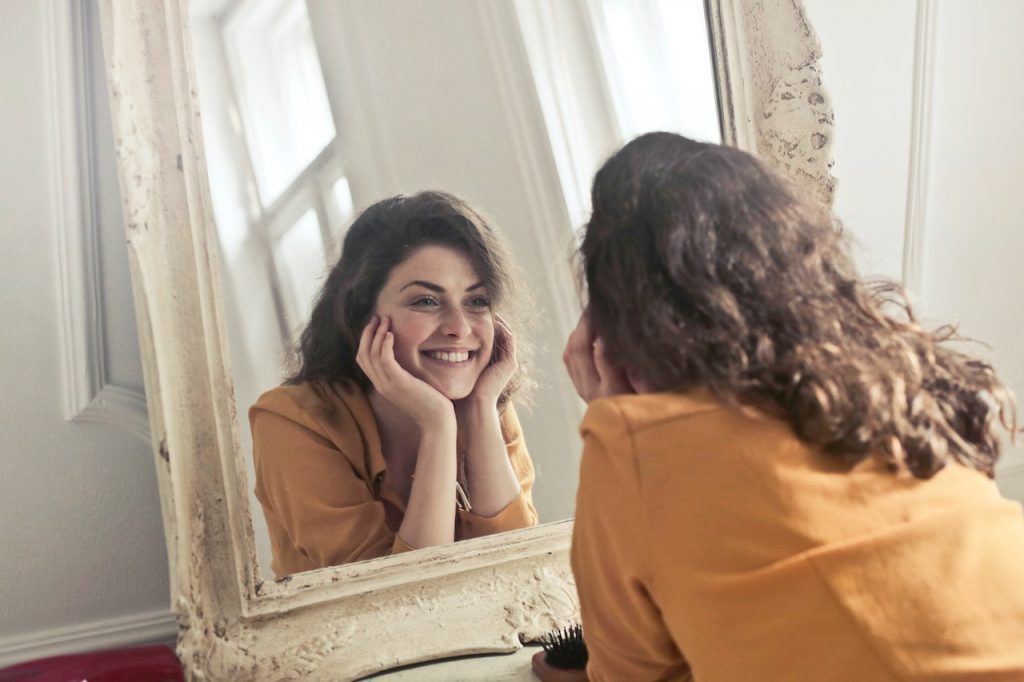 girl is looking at mirror and smiling