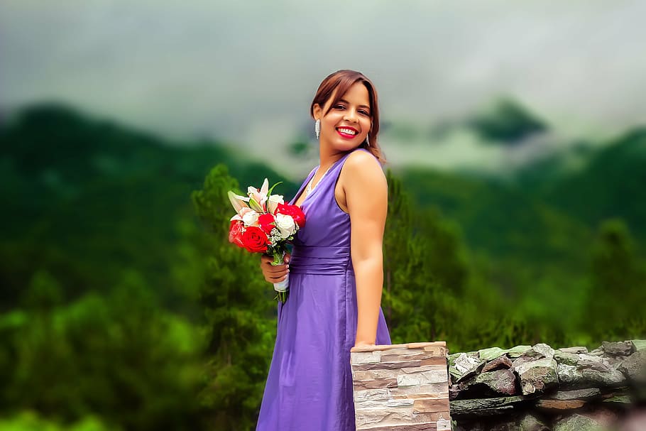 Dominican woman in purple one piece holding flowers in hand