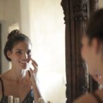 woman using serum on her face and smiling